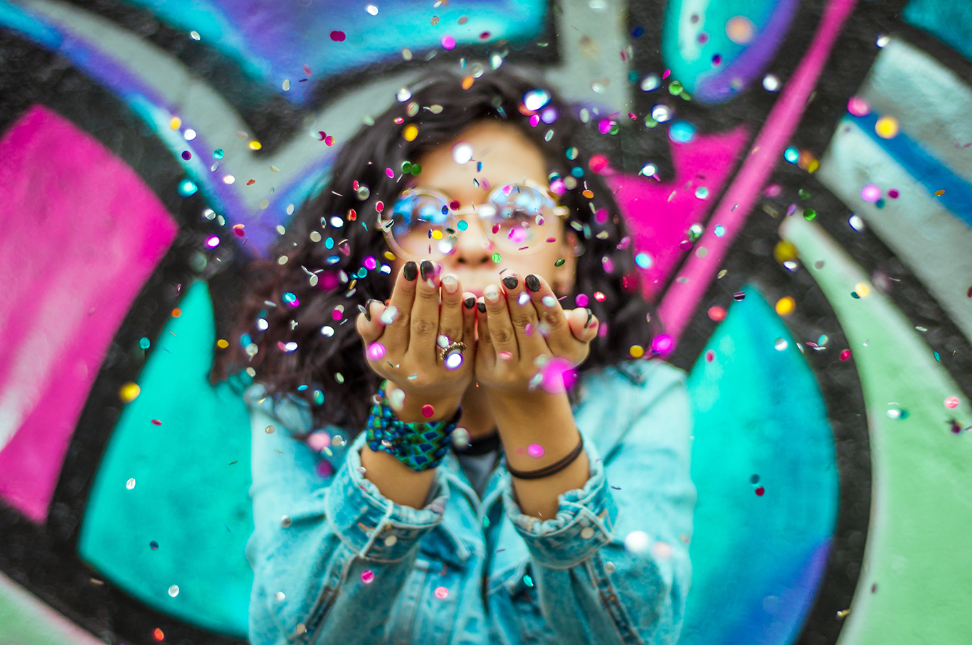 Photo of a person blowing confetti from her hands.
